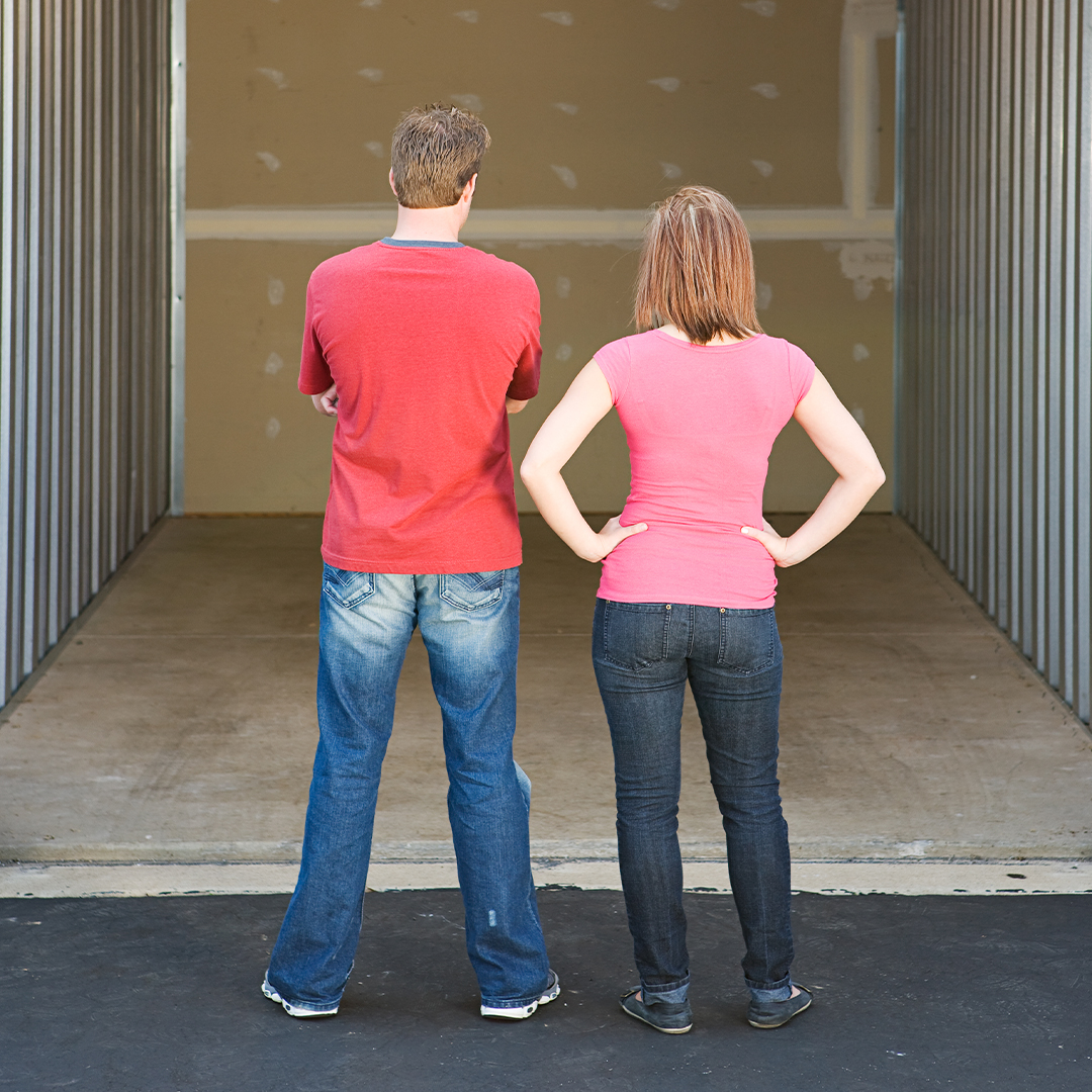 couple standing in front of an empty storage unit.